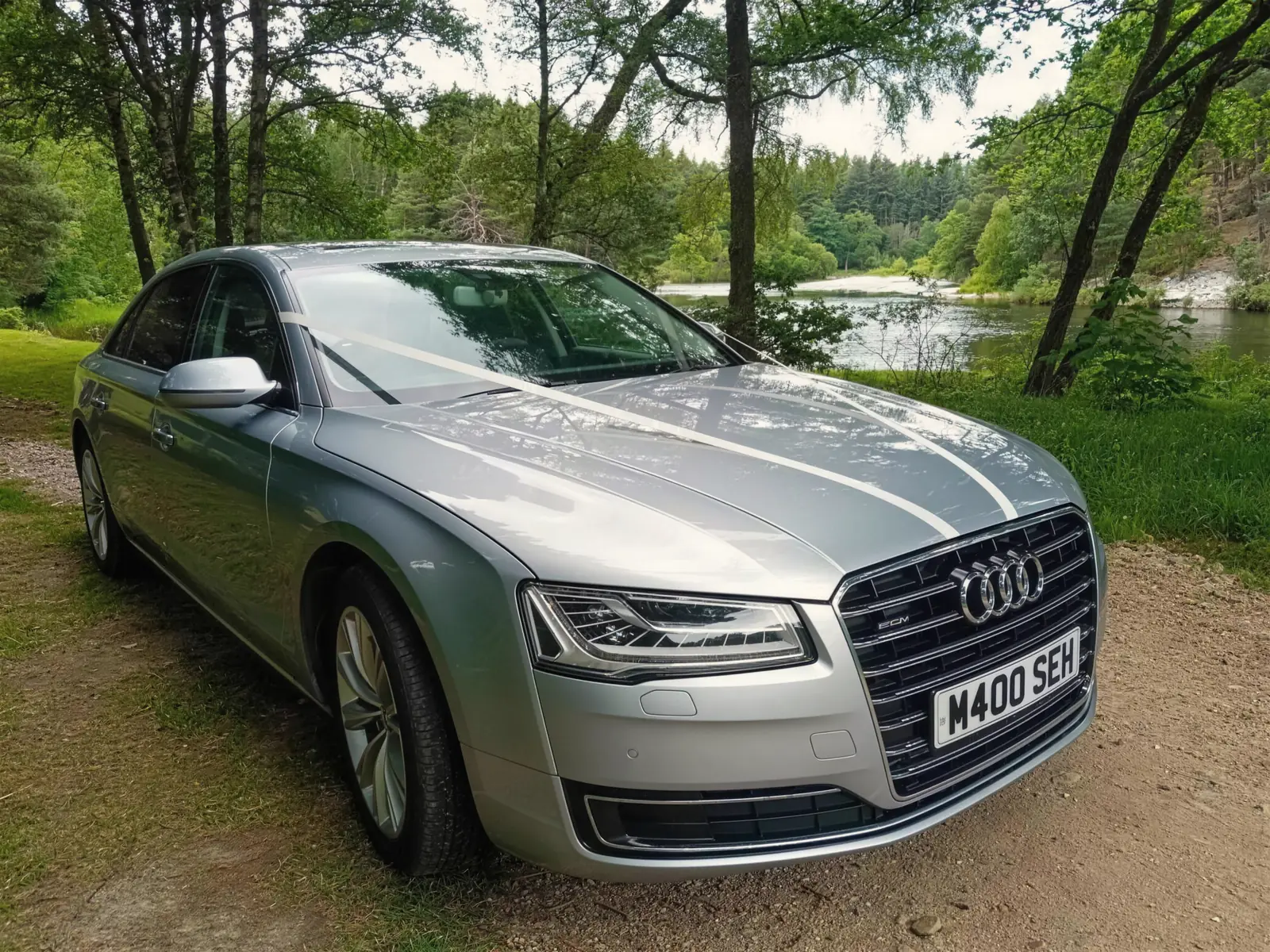 Audi A8 L with wedding ribbons beside a river